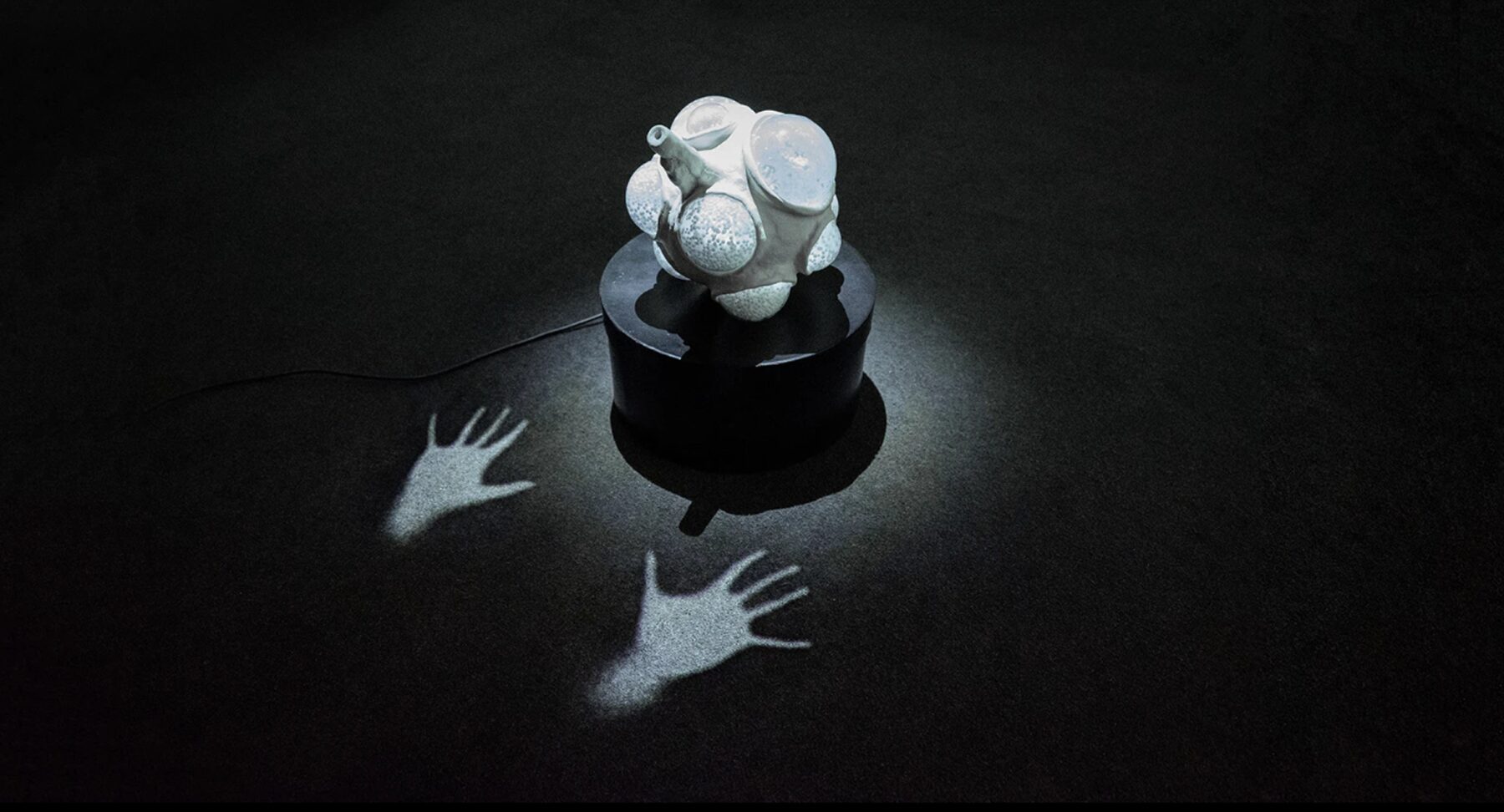Nexus installation on a black pedestal with projected handprints