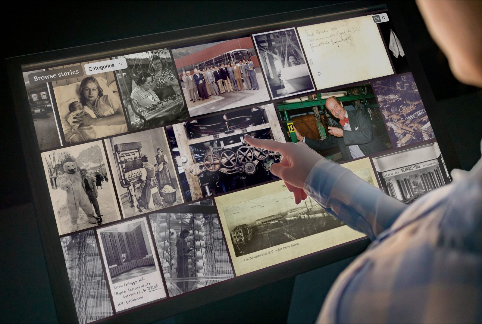 A visitor's hand pointing at archival photos on a multitouch table