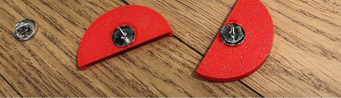 3D printed PLA prototypes of the Tap & Know pin with pin backs attached